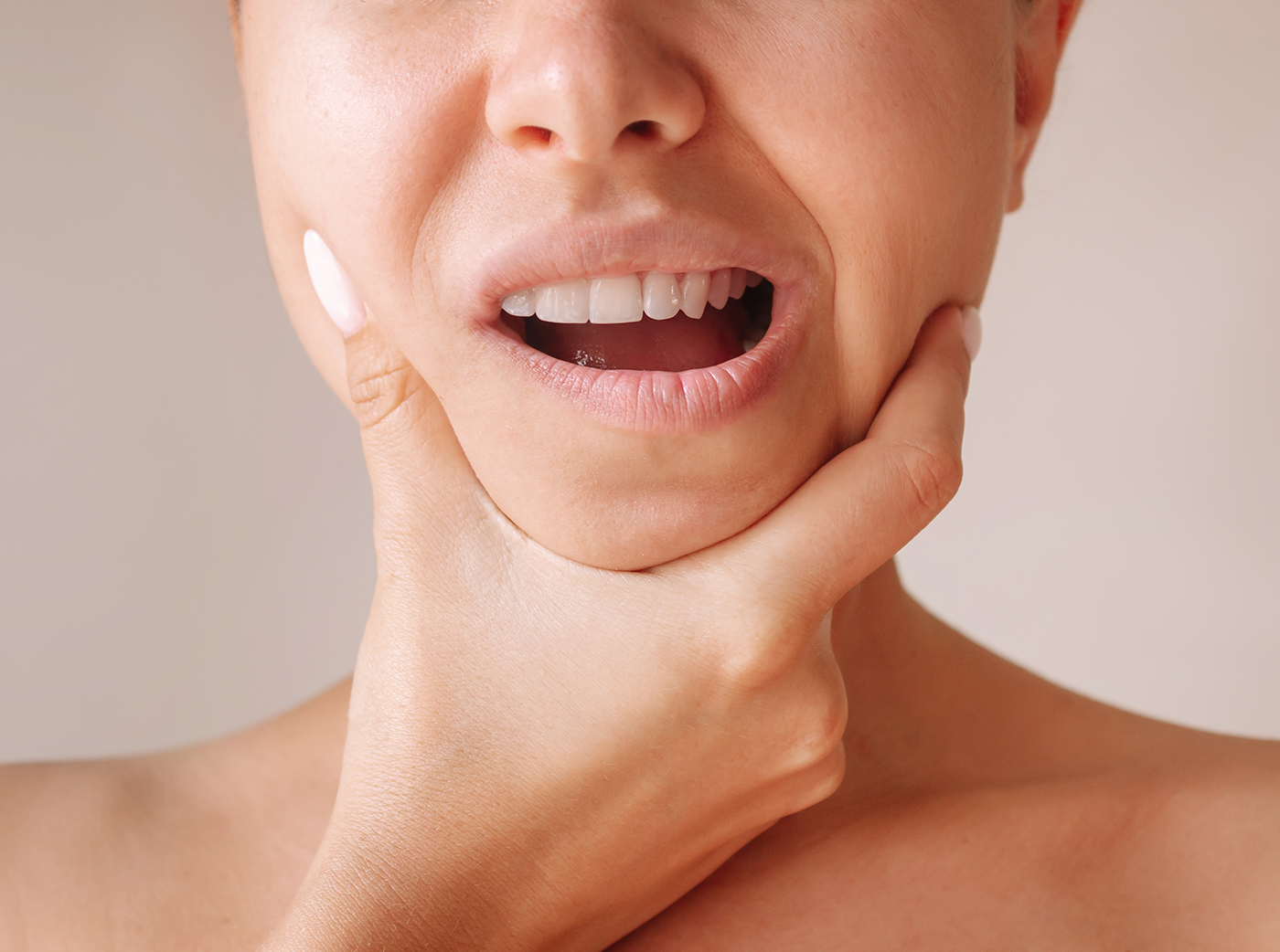 young woman suffering from jaw pain holding her jaw