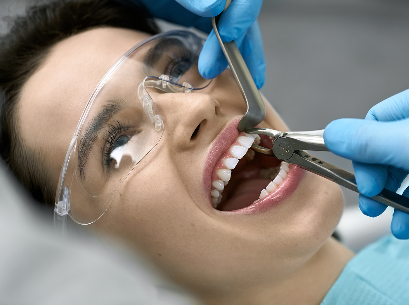 Pretty woman's teeth treatment in dental clinic tooth removal