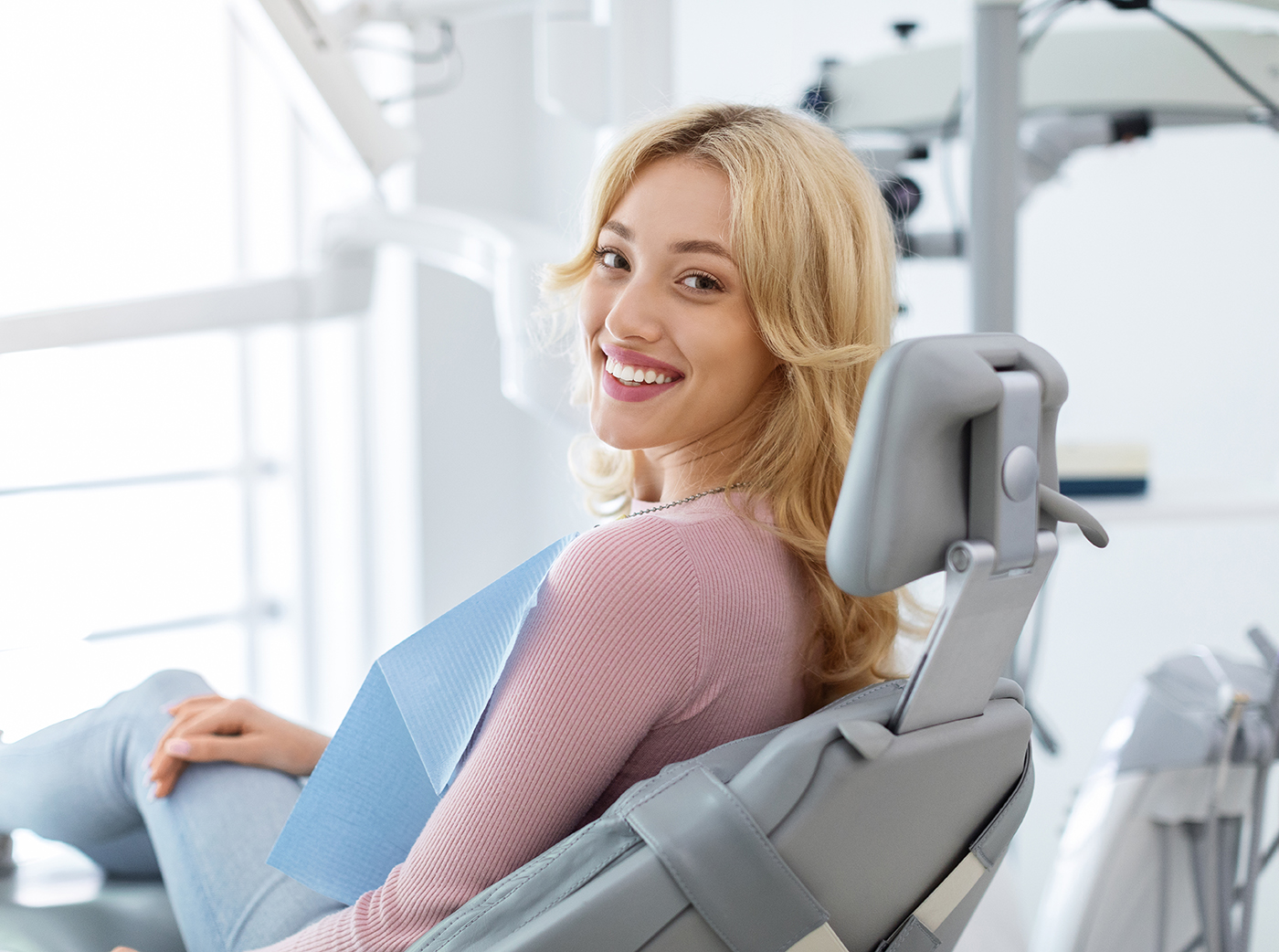 Smiling and relaxed young woman sitting at dental chair