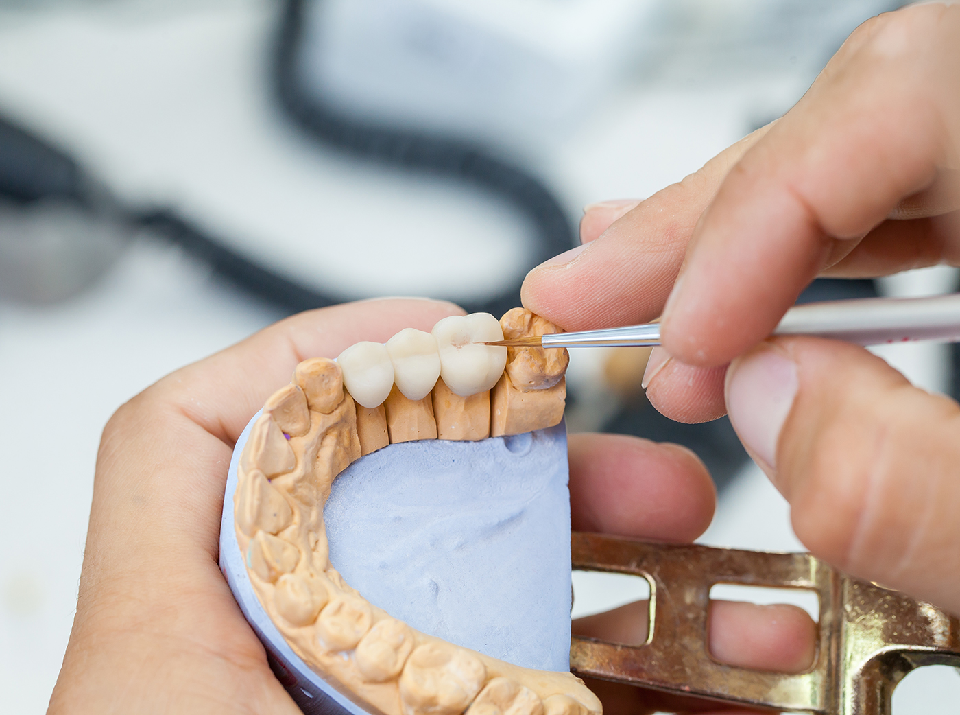 dental technician works by brush with dental bridge